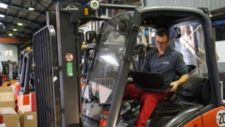 Techniker führt Inspektion eines Gebrauchtstaplers durch Techniker mit Laotop beim der Inspektion eines Staplers zur Aufbereitung